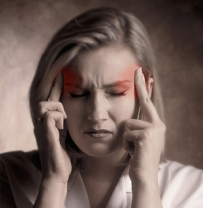 Picture of woman with closed eyes and a pained look on her face. She is massaging her temples with fingers from both hands.